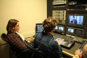 Grace Johnson-Glick and Ethan Messecar working in the control room at CAPS Media.