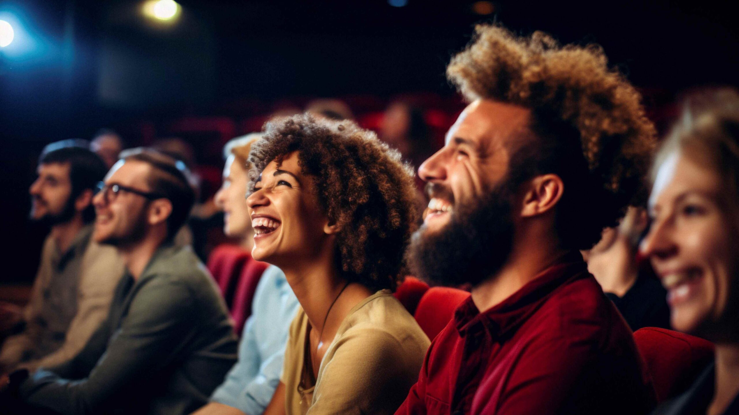 Audience members sitting in theater seats and laughing at the performance.