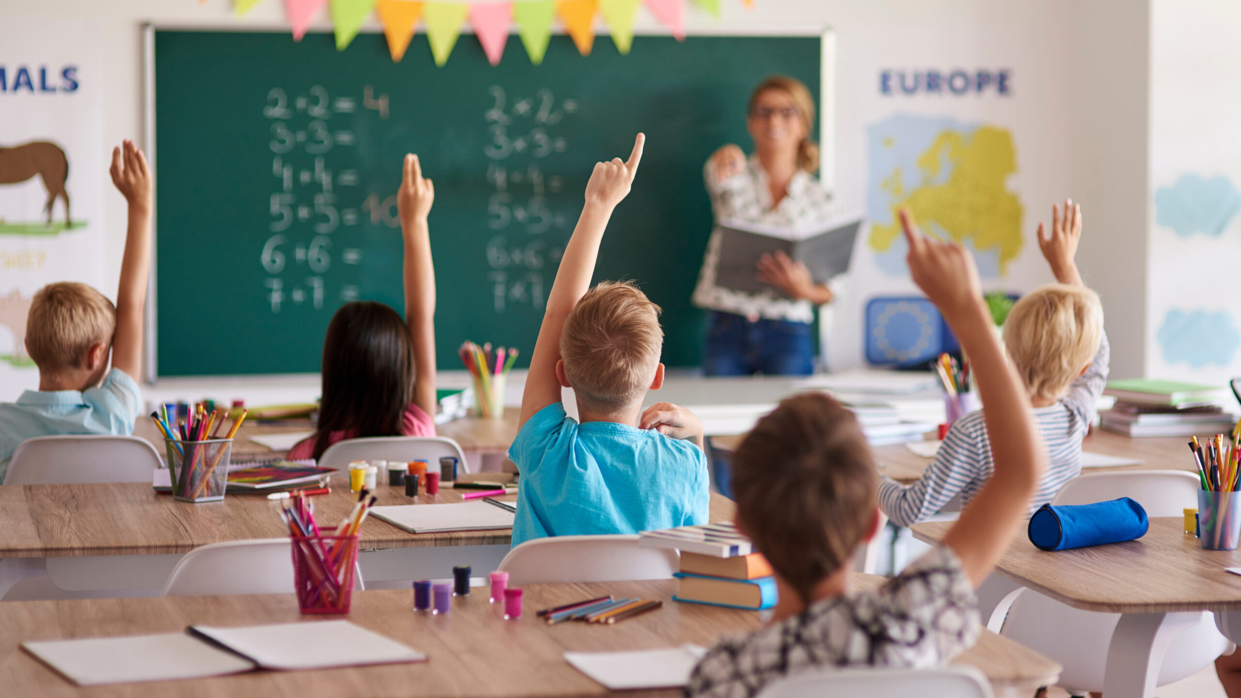 Children raising their hands in school.
