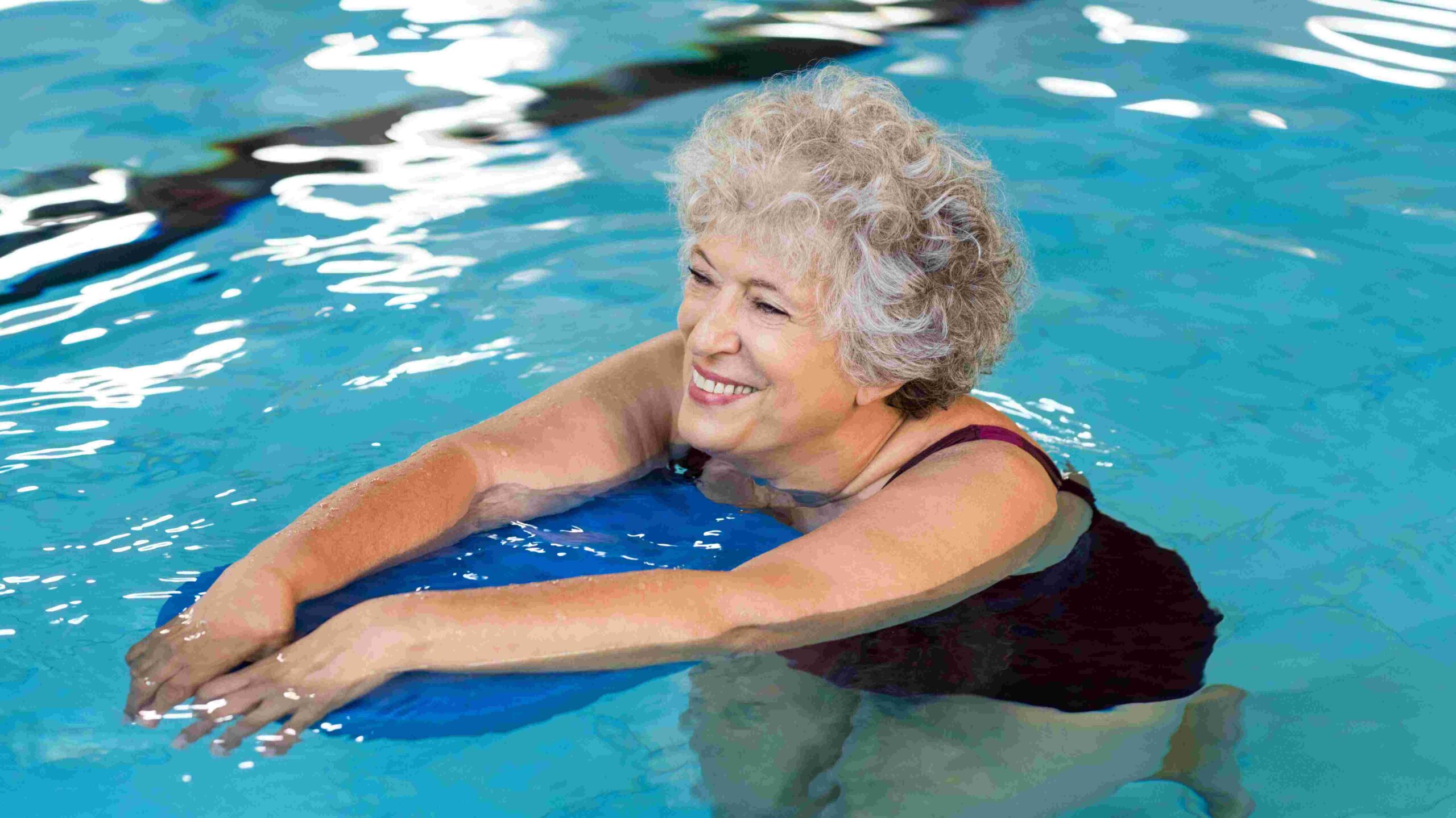 Senior woman smiling and swimming in a swimming pool