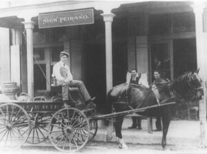Nicola “Nick” Peirano Sr, sitting in front of his family’s store – circa 1890.