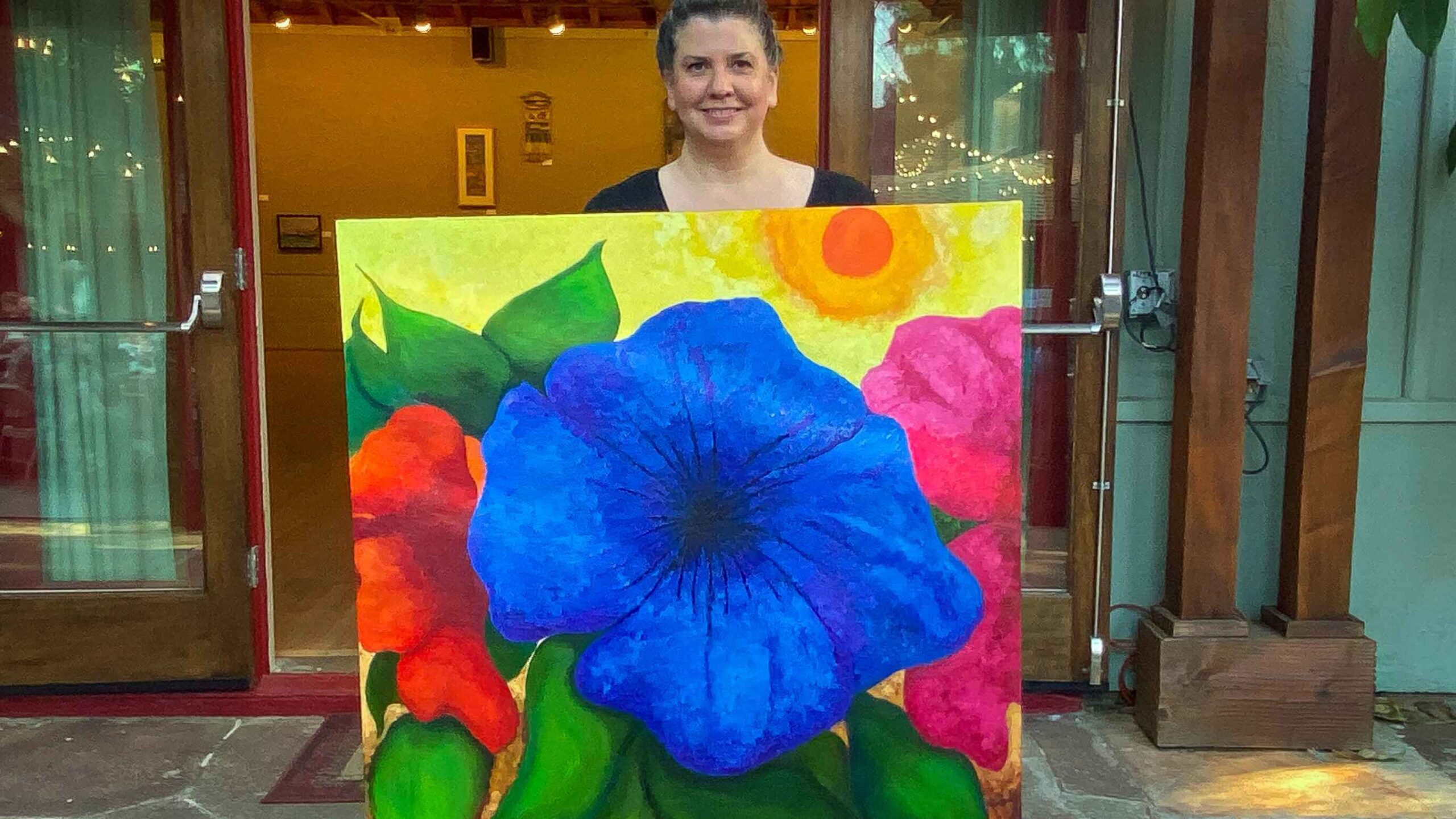 Jeannie Ethridge was one of many winners in the 2024 Great Art Theft. Holding a painting by Bonnie Caruk.