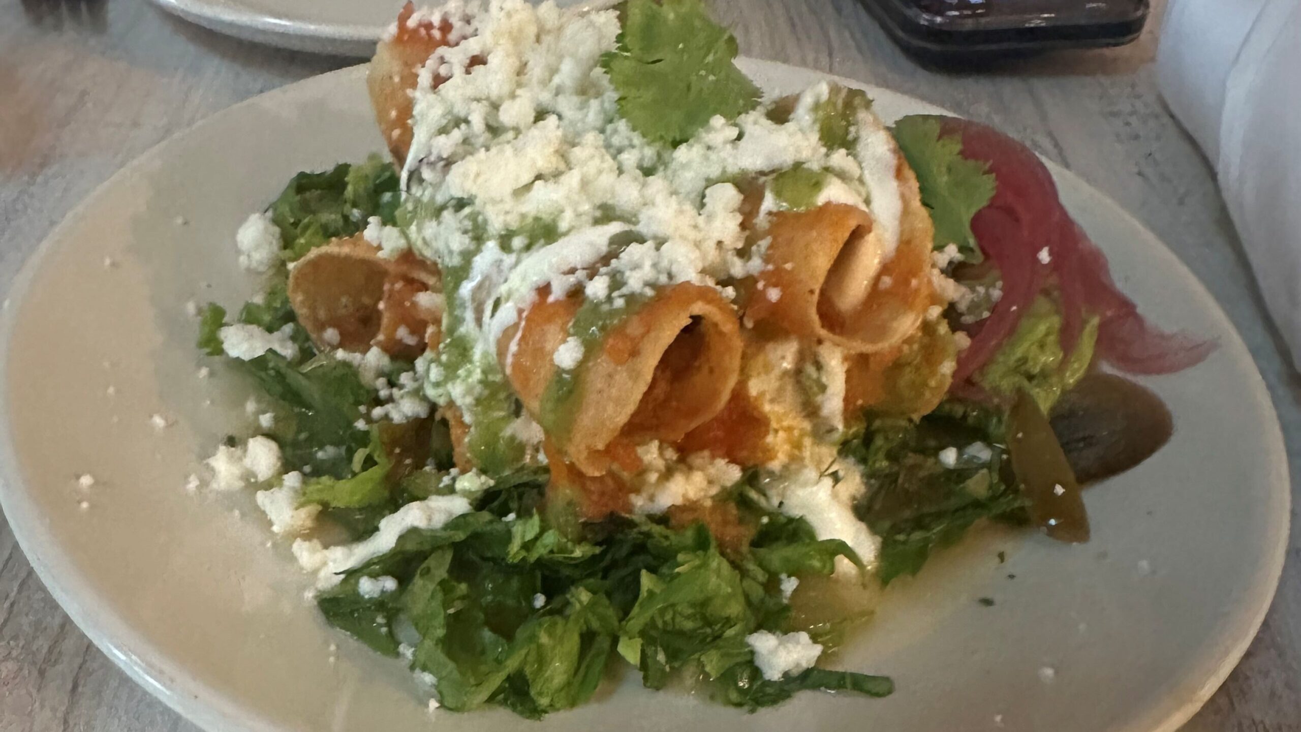 Rolled and crispy tacos filled with potato, cheese, and poblano atop a salad of tomato broth, crema, pickled jalapeño, salsa cruda, and guacamole.