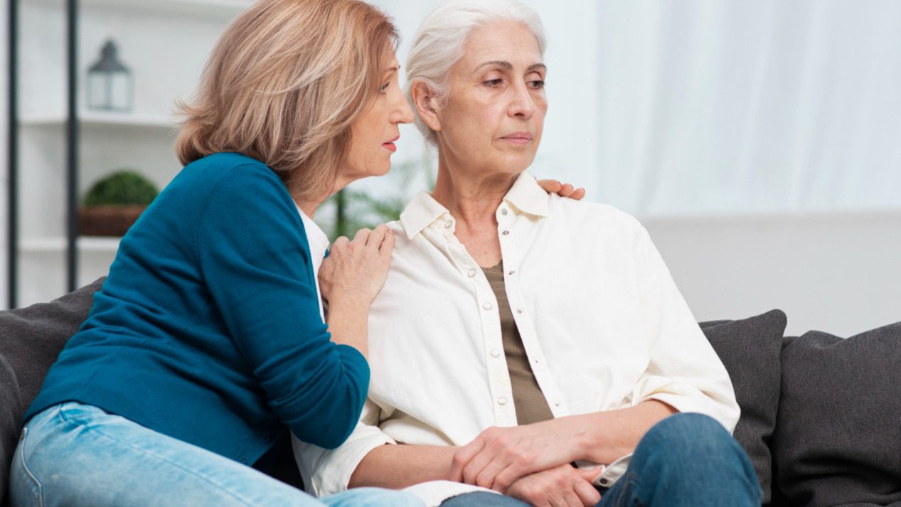 Senior woman being comforted by younger woman.