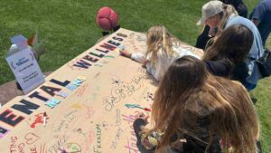 Women signing Mental Wellness cardboard