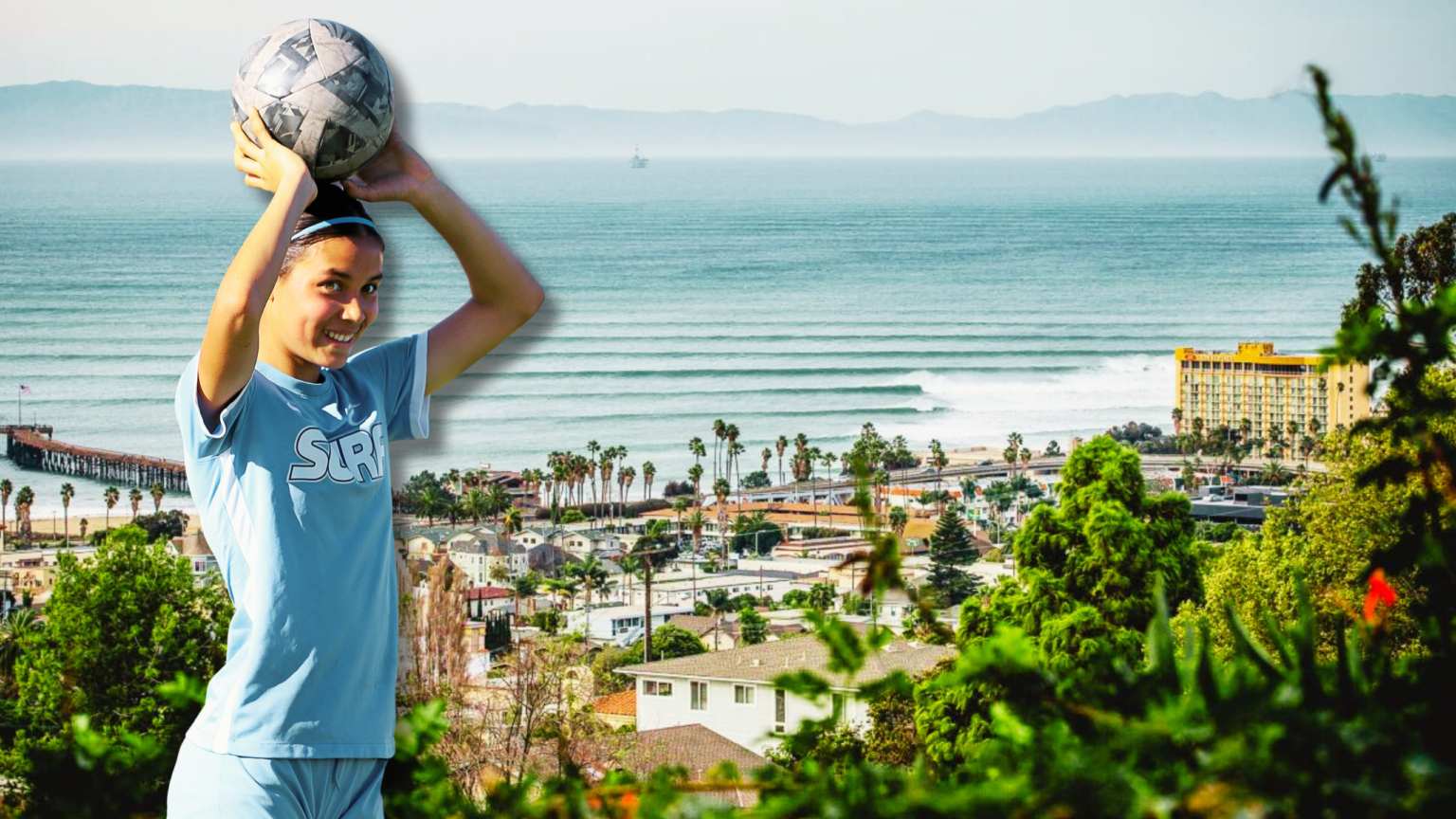 Girl holding soccer ball above head