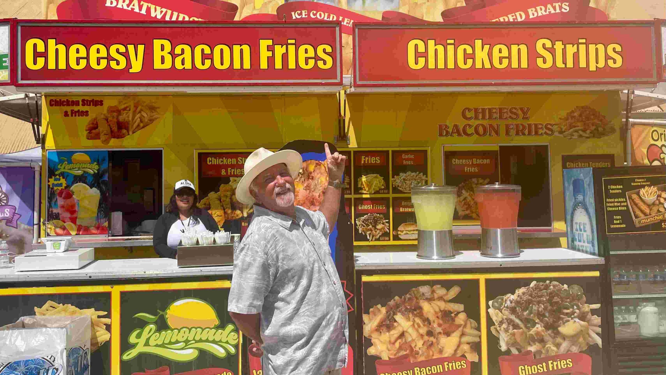 Senior man standing in front of food stand at Ventura Fair.