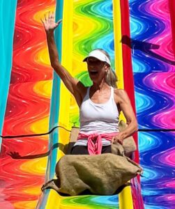 Senior woman sliding down a slide at Ventura Fair