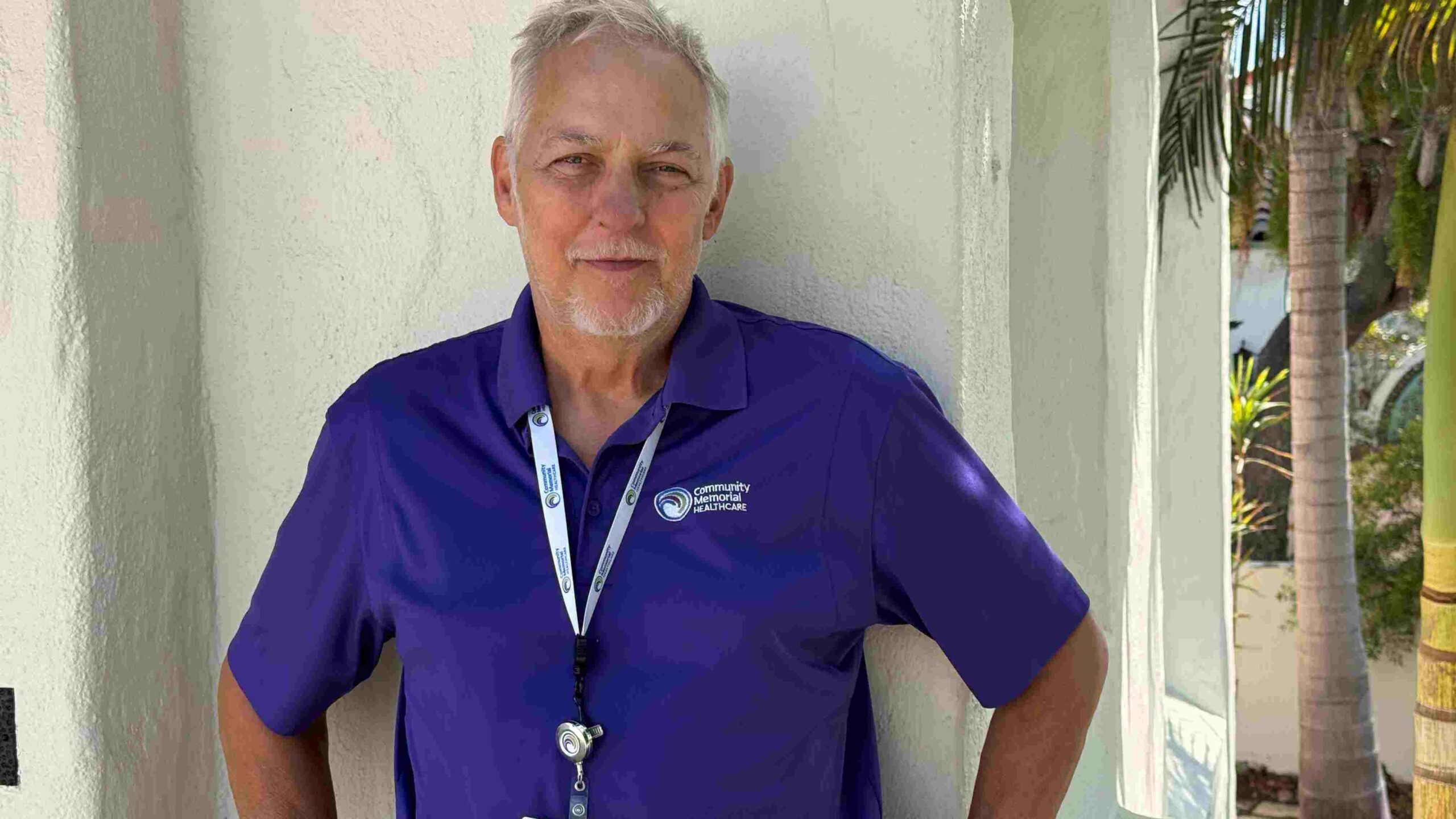 Dave Ramser standing in front of white door wearing his CMH volunteer uniform.