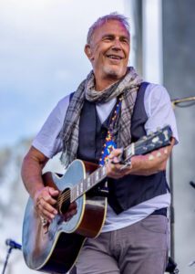 Costner playing guitar.
